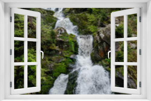 Fototapeta Naklejka Na Ścianę Okno 3D - Long exposure of a waterfall in a green forest with some stones and small plants in the foreground
