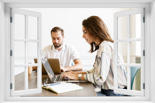 Concentrated couple colleagues work with laptops