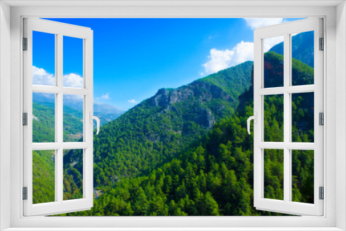 Fototapeta Naklejka Na Ścianę Okno 3D - Top view of high mountains covered by forest, blue sky with white clouds on a sunny summer day.
