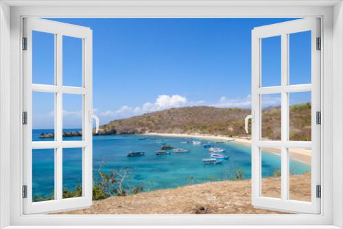 Fototapeta Naklejka Na Ścianę Okno 3D - A view on a bay on Pink Beach, Lombok Indonesia. Plenty colourful boats anchored to the shore. The water has many shades of blue. The heavenly beach is surrounded by small hills. Paradise beach.