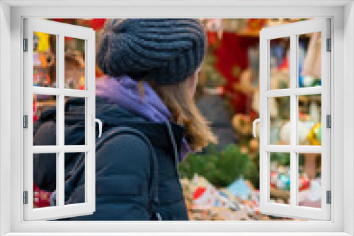 Fototapeta Naklejka Na Ścianę Okno 3D - woman chooses souvenirs at the Christmas market. back view. vertical photo