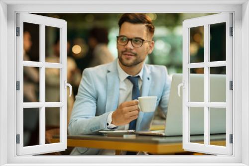 Businessman Using Laptop Whilst Working In Coffee Shop