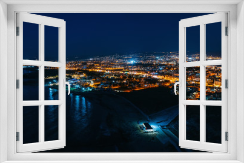 Fototapeta Naklejka Na Ścianę Okno 3D - Aerial panoramic view of Paphos, Cyprus seaside from above at night from drone. Beautiful evening mediterranean seascape with illuminated buildings and reflections of lights in sea water.