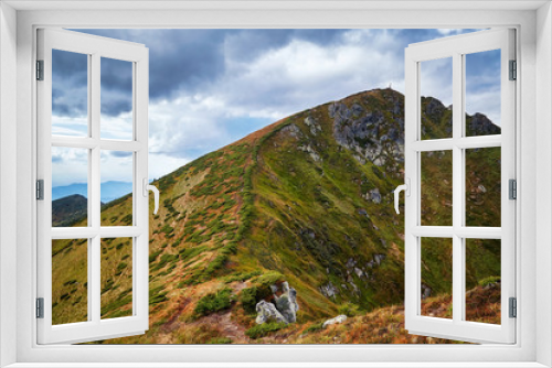 Fototapeta Naklejka Na Ścianę Okno 3D - Hiking path in green mountains peaks and hills with yellow grass outdoor view, autumn rural landscape with cloudy sky. Adventure mountain trekking concept. Moody light. Panoramic view background