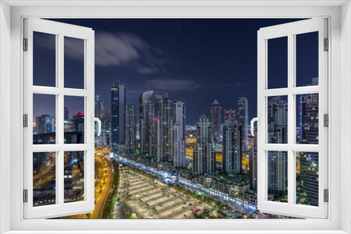 Fototapeta Naklejka Na Ścianę Okno 3D - Modern residential and office complex with many towers aerial night timelapse at Business Bay, Dubai, UAE.