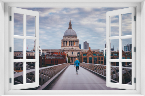 Fototapeta Naklejka Na Ścianę Okno 3D - Young active man running at Millennium Footbridge over the Thames, St Paul's Cathedral in background