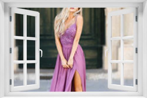 Portrait of a young blonde woman who is standing in the city against the background of doors.