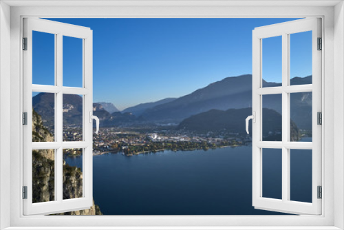 Fototapeta Naklejka Na Ścianę Okno 3D - Steep cliff, view of the city of Riva del Garda, Italy. Panoramic view of Lake Garda in the foreground, the city is surrounded by rocks and alpine mountains. Autumn season.