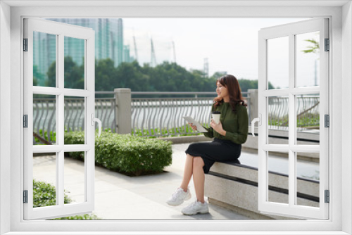 Pretty young woman with beautiful smile using tablet in the park