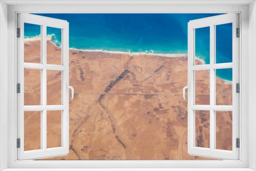 Fototapeta Naklejka Na Ścianę Okno 3D - Earth's line. A perspective of the ground's colors and shapes. Aerial view of the Egyptian coast overlooking the Mediterranean sea. View from the airplane window. Sea with fantastic turquoise colors