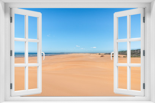 Fototapeta Naklejka Na Ścianę Okno 3D - Sandstrand mit Himmel und kleinen Wolken Meer auf der linken Seite Büsche auf der Rechtenseite ein sonniger Tag