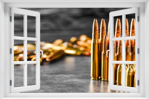 Fototapeta Naklejka Na Ścianę Okno 3D - Various kind of bullets or ammonution on dark stone table. Bullet pile in war ammo background. Magazines, rounds and military technology. Wide banner or panorama guns photo..