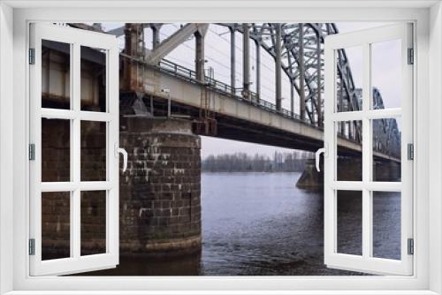 Fototapeta Naklejka Na Ścianę Okno 3D - Railroad Bridge over the Daugav River in Riga with a detailed view on the pillar structures on a cold and dull winter day