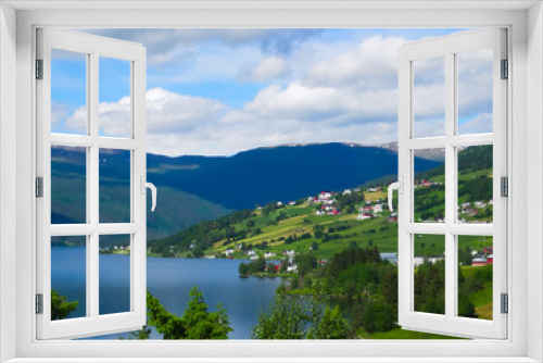 Fototapeta Naklejka Na Ścianę Okno 3D - A beautiful Norwegian mountain landscape with fjord and farms in spring with blue sky and clouds.