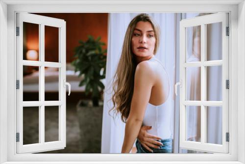 Young woman standing by the window in the room