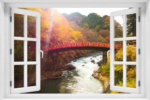 Fototapeta Naklejka Na Ścianę Okno 3D - Red bridge over flowing river stream with autumn leaves and sunlight