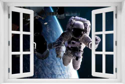 Fototapeta Naklejka Na Ścianę Okno 3D - Astronaut at spacewalk with space station at background. Elements of this image furnished by NASA