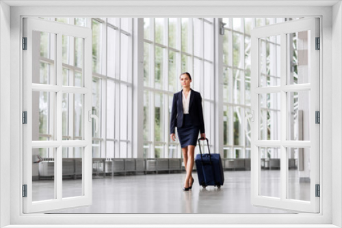 business trip, corporate and people concept - young businesswoman walking with travel bag along office building or airport