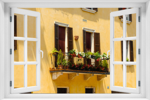 Fototapeta Naklejka Na Ścianę Okno 3D - Italian colorful windows with open wooden shutters and fresh flowers. Beautiful european porch decorated with flowers in Italy. Brick wall of an old historical town in Padova, Italy.