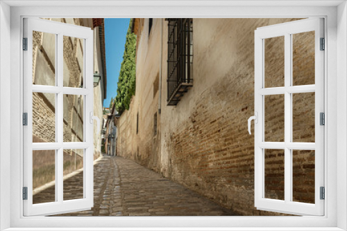 Fototapeta Naklejka Na Ścianę Okno 3D - Narrow alley in the old town of Granada, Andalusia Spain. Low angle perspective of a picturesque narrow street in Granada, Spain.