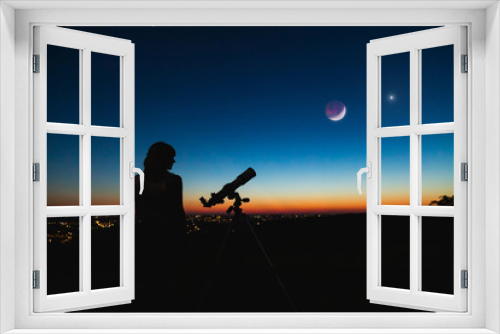 Fototapeta Naklejka Na Ścianę Okno 3D - Astronomer with a telescope watching at the stars and Moon with blurred city lights in the background.