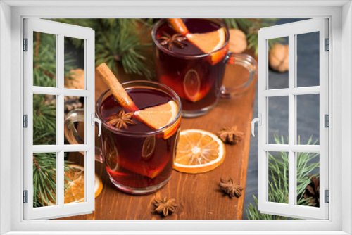 Fototapeta Naklejka Na Ścianę Okno 3D - Christmas mulled wine with orange slices on the basis of red wine with spicy cinnamon sticks, star anise, on a black background. The view from the top.