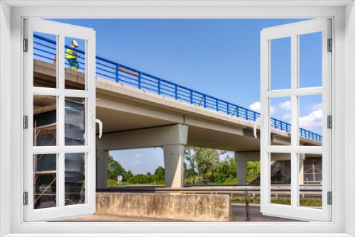 Fototapeta Naklejka Na Ścianę Okno 3D - Worker mount renewing blue fence on overpass over highway