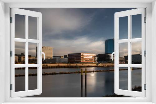 Fototapeta Naklejka Na Ścianę Okno 3D - long exposure of the Überseestadt in Bremen, Germany with office buildings and cloudy sky during sunrise