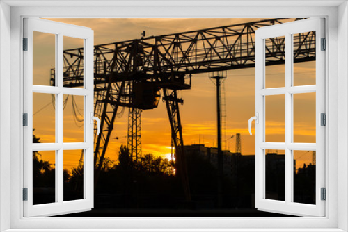 Fototapeta Naklejka Na Ścianę Okno 3D - overhead crane at the railway station. Crane silhouette on sunset background. Heavy industry concept.