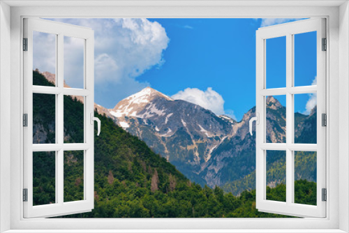 Fototapeta Naklejka Na Ścianę Okno 3D - Julian Alps mountains on Bohinj Lake in Slovenia. Alpine Nature in Slovenija. View of green forest. Beautiful landscape in summer. Travel destination. Scenic background with blue sky and white clouds