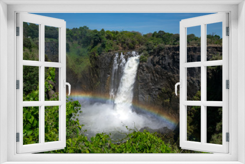 Fototapeta Naklejka Na Ścianę Okno 3D - Large stream of water is flowing from the Zambezi river in to the Victoria Falls, with on top a rainbow.