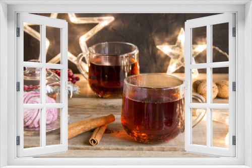 Fototapeta Naklejka Na Ścianę Okno 3D - winter tea party with dessert in a glass capsule on a wooden table. Christmas lights garland of stars, walnuts and cinnamon sticks for a cup of tea. Christmas mood
