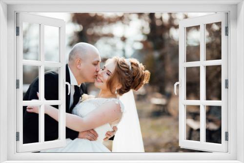 Elegant bride and groom posing together outdoors in a park on a wedding day. Elegant bride and groom posing together outdoors on a wedding day. Wedding dress. Relationship love concept. 