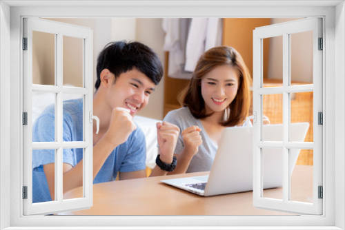 Beautiful portrait young asian couple working laptop with smile and happy sitting in bedroom, man and woman using notebook computer with excited and satisfied, business and success concept.