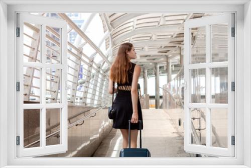 Young Caucasian woman walking with suitcase in modern airport terminal.Back view of a happy traveler.