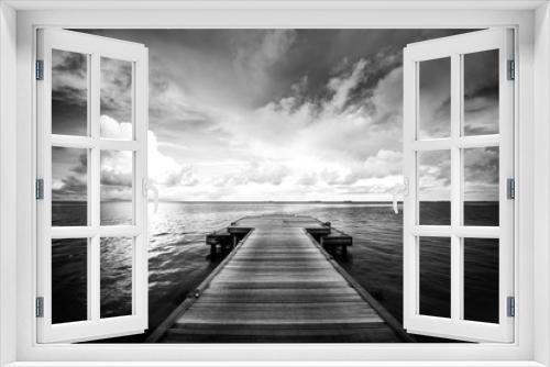 Fototapeta Naklejka Na Ścianę Okno 3D - Idyllic or dramatic bungalow on water, Maldive Islands. Dramatic black and white process for loneliness or inspiration. Perspective view at sea from center of wooden pier dramatic sky at daylight.