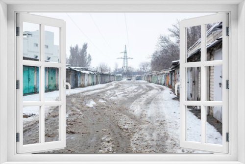 Fototapeta Naklejka Na Ścianę Okno 3D - Winter dirty broken road in a garage cooperative. Gray depressing moody winter