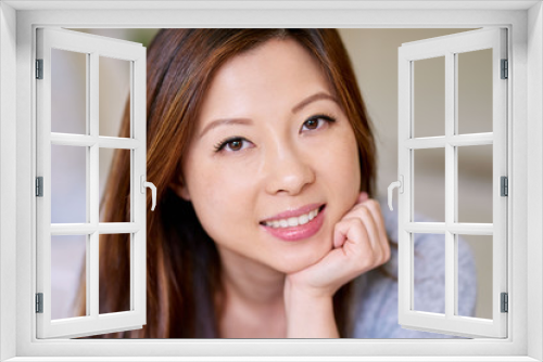 Smiling Asian woman with perfect skin relaxing on her bed