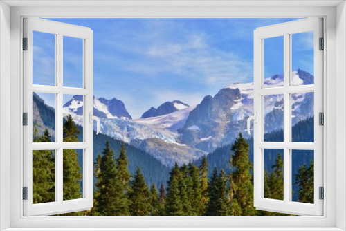 Fototapeta Naklejka Na Ścianę Okno 3D - High mountains are covered with glacier, forest is growing in the foreground. Sun is shining, sky is blue, Canada. 