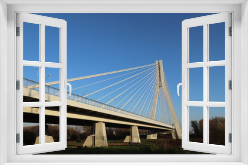 Fototapeta Naklejka Na Ścianę Okno 3D - Rzeszow, Poland - 9 9 2018: Suspended road bridge across the Wislok River. Metal construction technological structure. Modern architecture. A white cross on a blue background is a symbol of the city