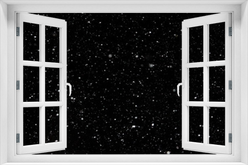 Snowstorm on a black background, white snowflakes swirling.