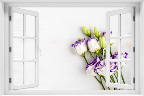 Fototapeta Naklejka Na Ścianę Okno 3D - Beautiful Eustoma, white petals with violet borders on white wooden background with copy space. Lisianthus flowers. Top view. Soft focus. flat lay. Floral decor for presentation of natural cosmetics.