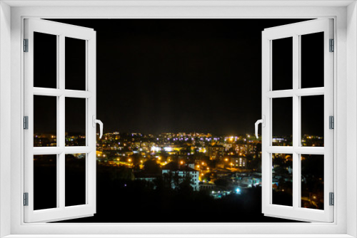 Fototapeta Naklejka Na Ścianę Okno 3D - View of the night city in the street lights and the light in the windows of the houses. Night city landscape.