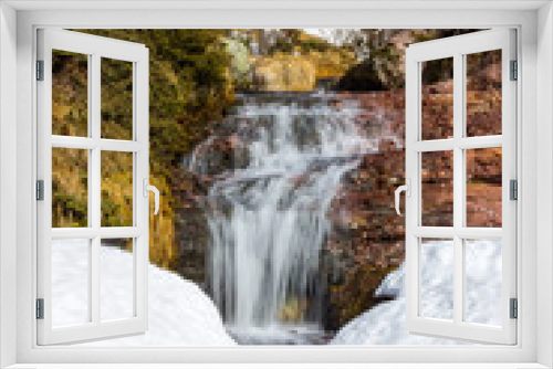 Fototapeta Naklejka Na Ścianę Okno 3D - Low perspective view of large, scenic, beautiful waterfall water falling from red rocky cliff under the snow