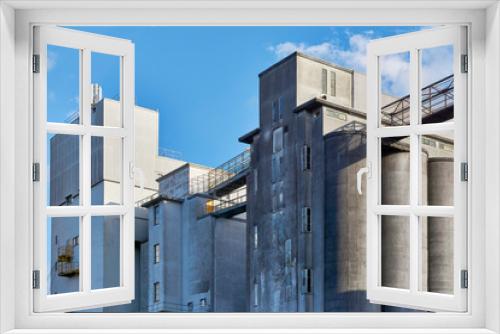 Fototapeta Naklejka Na Ścianę Okno 3D - Old industrial buildings made of concrete against a blue sky. Concept of recession or economic growth. 