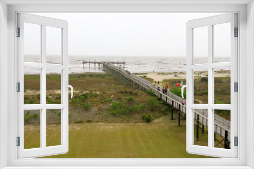 Fototapeta Naklejka Na Ścianę Okno 3D - Louisiana nature background. Way to the beach and pier along wooden boardwalk over the sand dunes at the Grand Isle State Park, Louisiana, South USA. Red flag marks beach closed for swimming.
