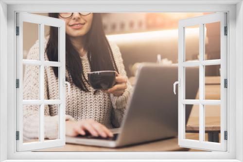 Woman student doing home work with laptop in urban cafe