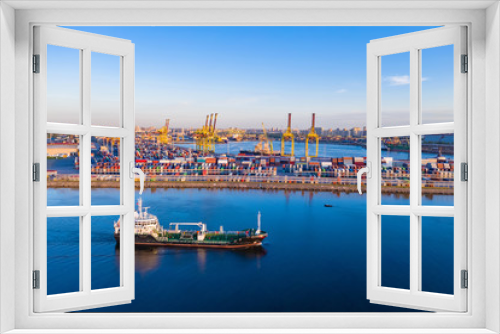 Fototapeta Naklejka Na Ścianę Okno 3D - Cargo ship is on the fairway. Sea commercial port. On the pier are containers with goods. Cranes carry out loading and unloading. Transportation of goods by sea. Panorama of the port.