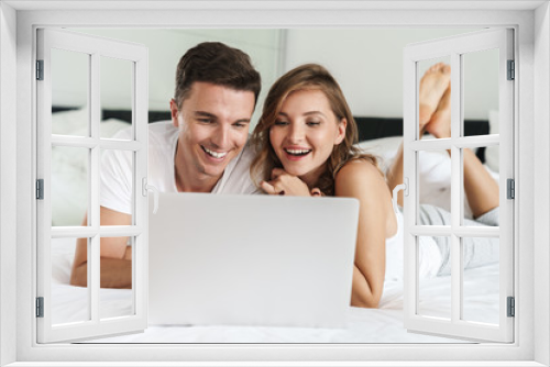 Attractive happy young couple laying on bed in the bedroom