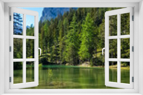 Fototapeta Naklejka Na Ścianę Okno 3D - A peaceful view on an Alpine valley in Austria. The valley has a Green Lake in the middle. Early spring in the mountains. There is a high mountain range in the back. Freshness. Few ducks on the lake.